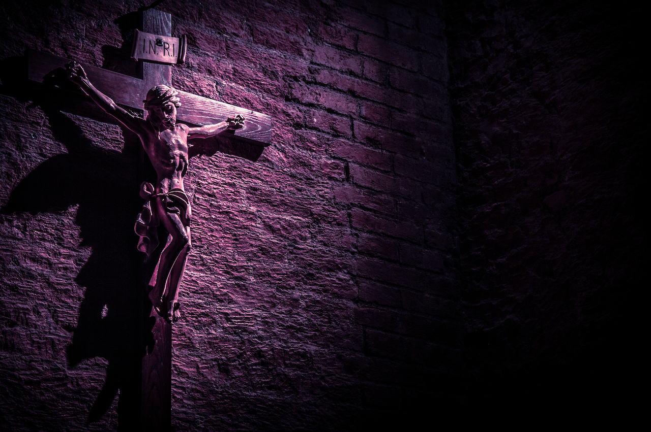 Crucifix on brick wall in shadow
